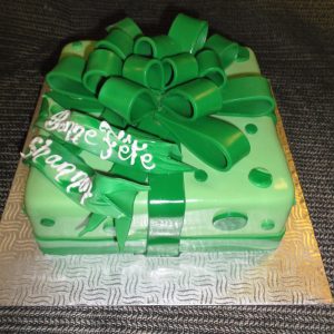 Gâteau en pâte de sucre en forme de cadeau. Décoré d'un ruban et d'un chou vert, avec des pois verts.