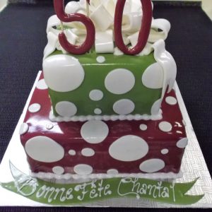 Gâteau 50e anniversaire à pois blancs sur fonds vert et rouge. Une belle pièce 2 étages en pâte de sucre.