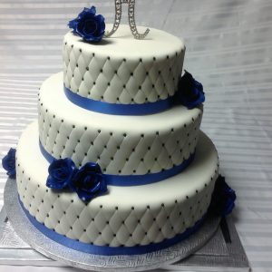 Élégant gâteau de mariage 3 étages fait sur mesure, avec des fleurs bleues faites en pâte de sucre. Fait sur mesure, pour plus d'information contactez-nous.