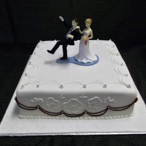 Gâteau de mariage en pâte de sucre. Figurine des mariés montrant la mariée tirant son mari par le collet. Fait sur mesure, pour plus d'information contactez-nous.