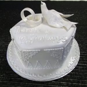 Gâteau de mariage en forme de porte-alliance. Avec anneaux de mariage et colombe blanche en pâte de sucre. Fait sur mesure, pour plus d'information contactez-nous.